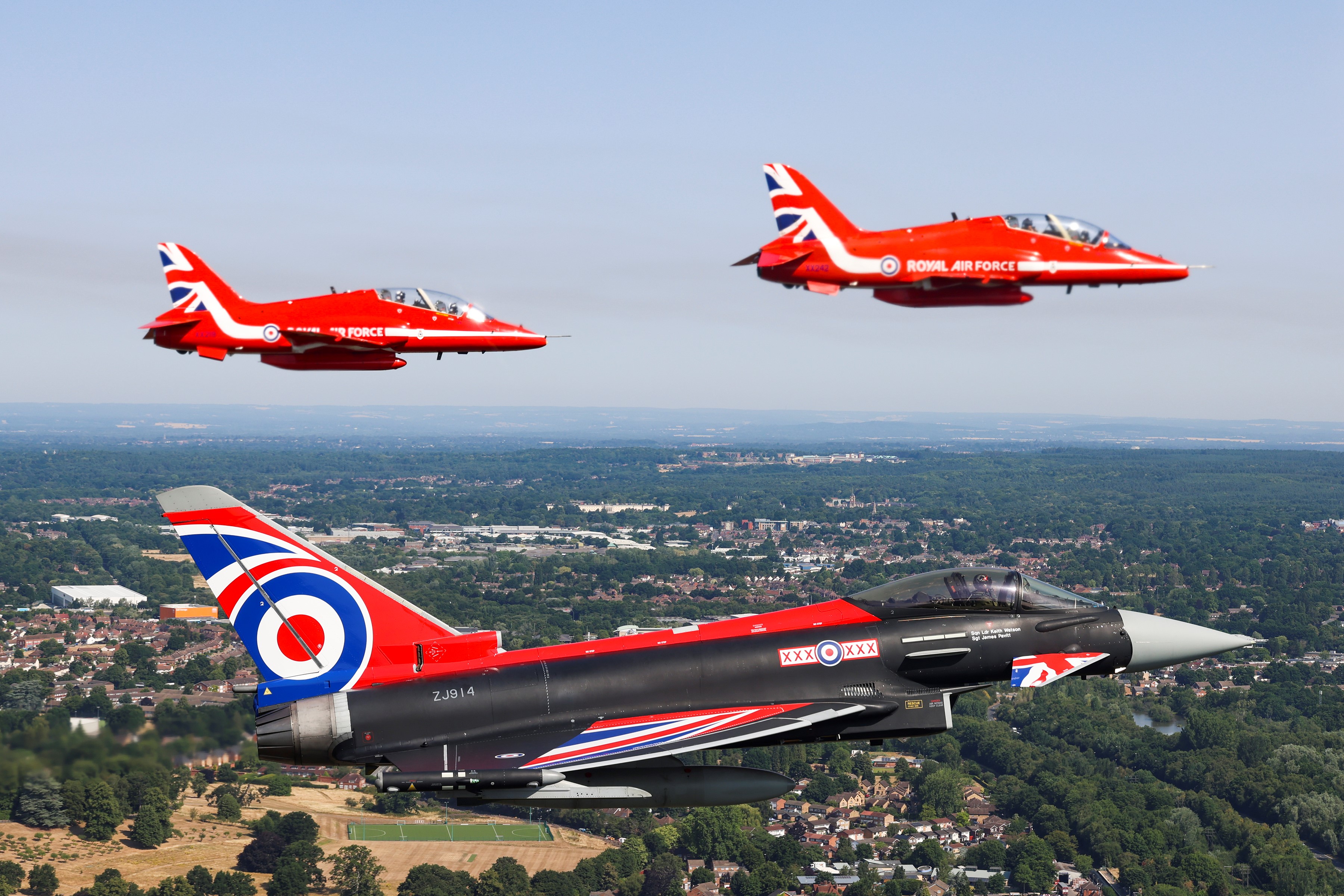 Image shows Red Arrows performing in formation over airfield.